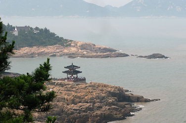 Covered overlook on the water's edge with mountains in the background